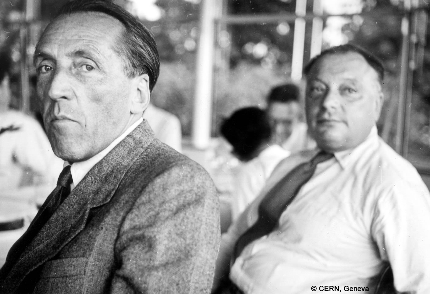 Paul Scherrer sitzt neben Wolfgang Pauli, beide blicken in dieselbe Richtung