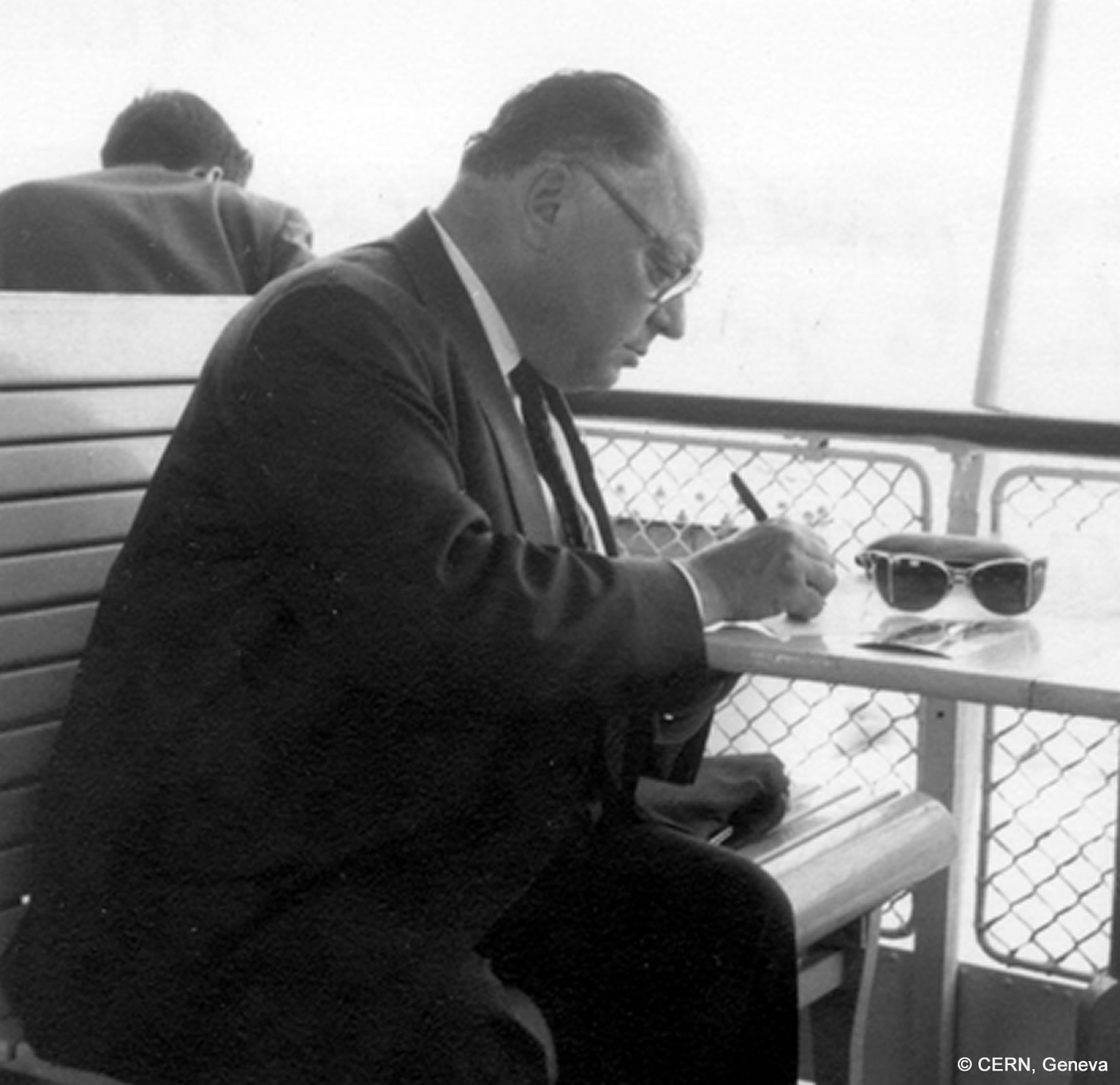 Wolfgang Pauli sitzt schreibend an einem Tischchen auf einem Schiff