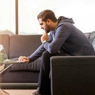 A man sits on the sofa and learns online