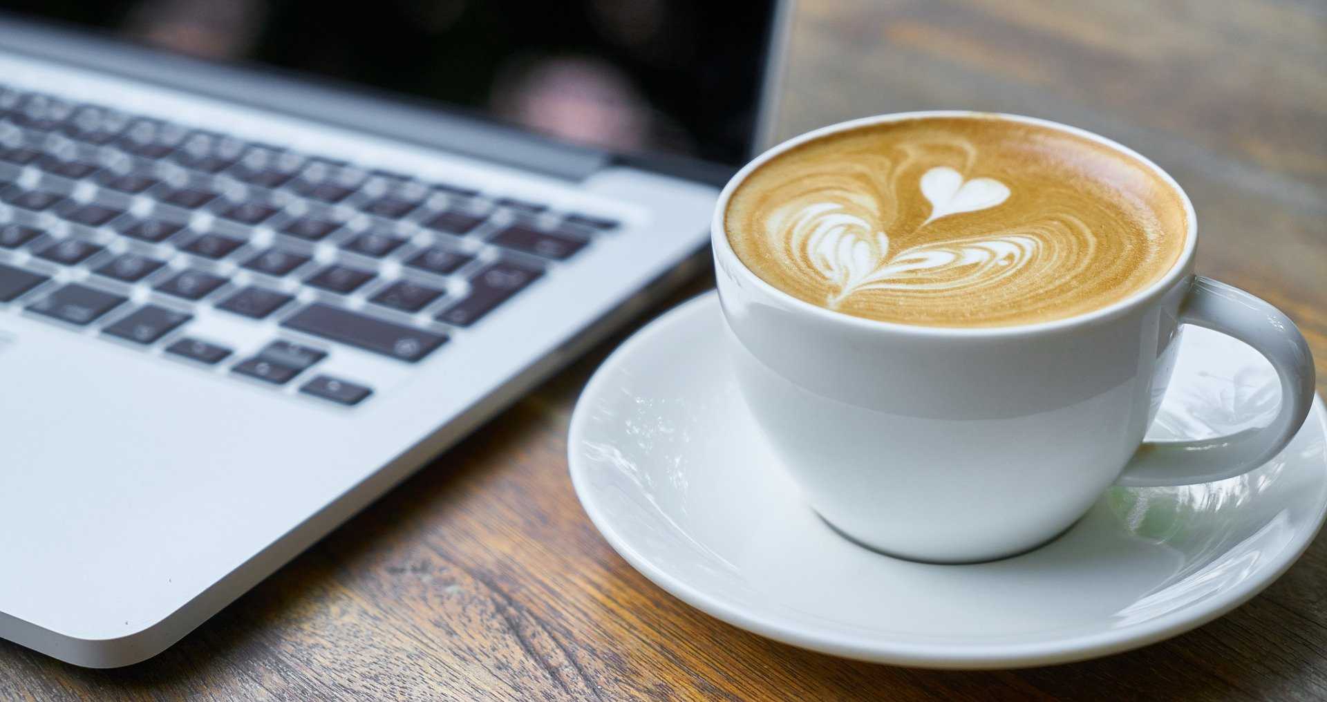 Laptop und Kaffeetasee auf Tisch