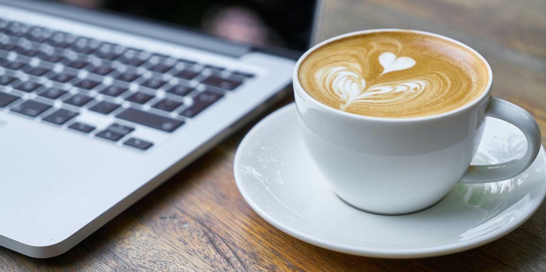 Laptop und Kaffeetasse auf Tisch