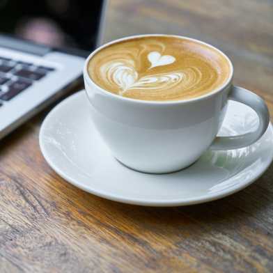 Laptop und Kaffeetasse auf Holztisch