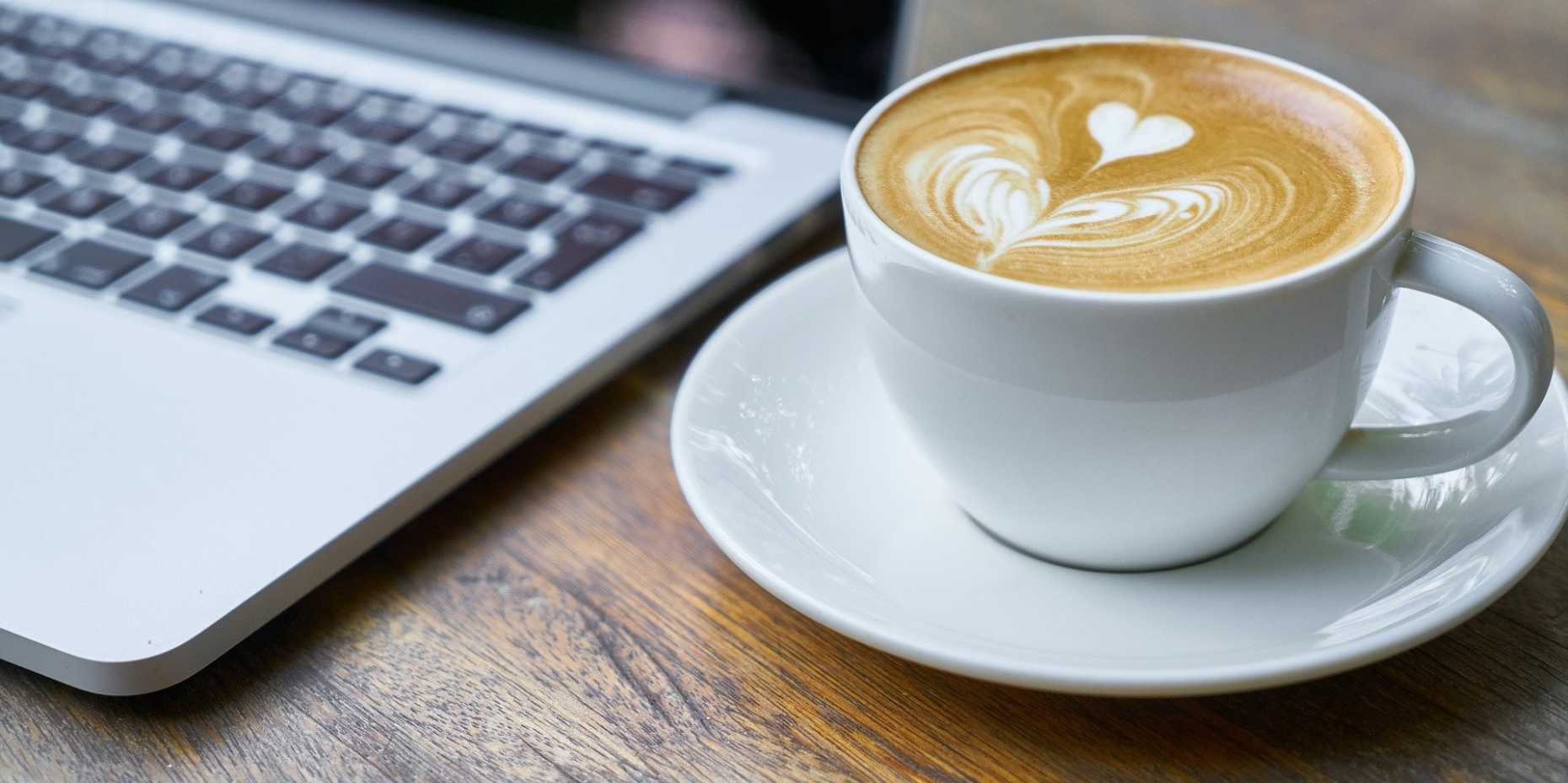 Kaffee neben MacBook auf Holztisch