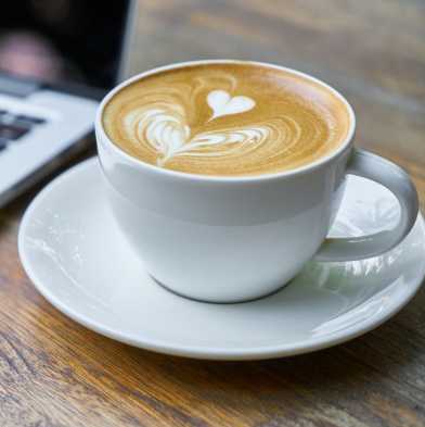 Kaffee neben MacBook auf Holztisch