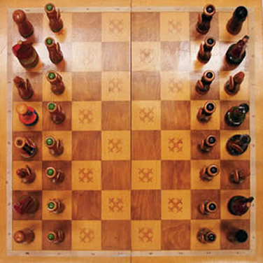 Ein Schachbrett mit 8x8 weissen und braunen Feldern. Die gegnerischen Schachfiguren befinden sich in der Anfangsposition am jeweils anderen Rand des Feldes.
