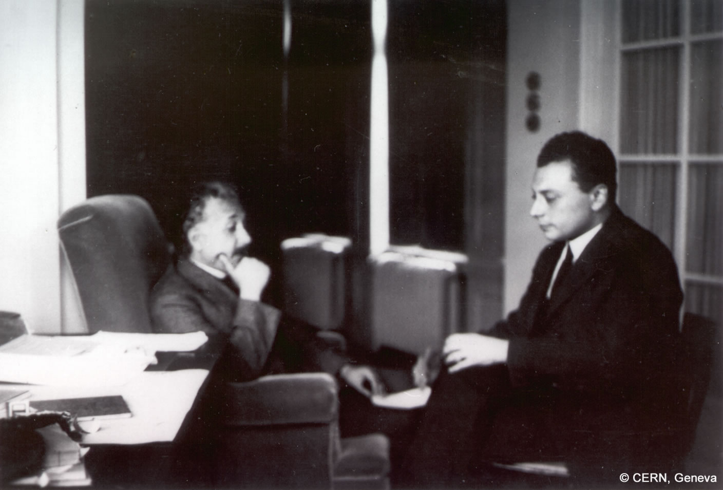 Wolfgang Pauli und Albert Einstein sitzen vs-à-vis voneinander und wirken nachdenklich
