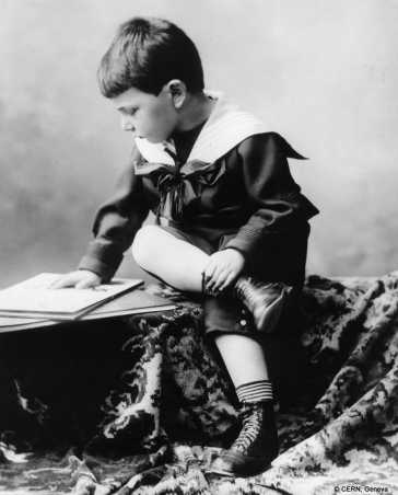 Wolfgang Pauli als kleiner Junge, der mit verschränkten Beinen sitzt und liest.